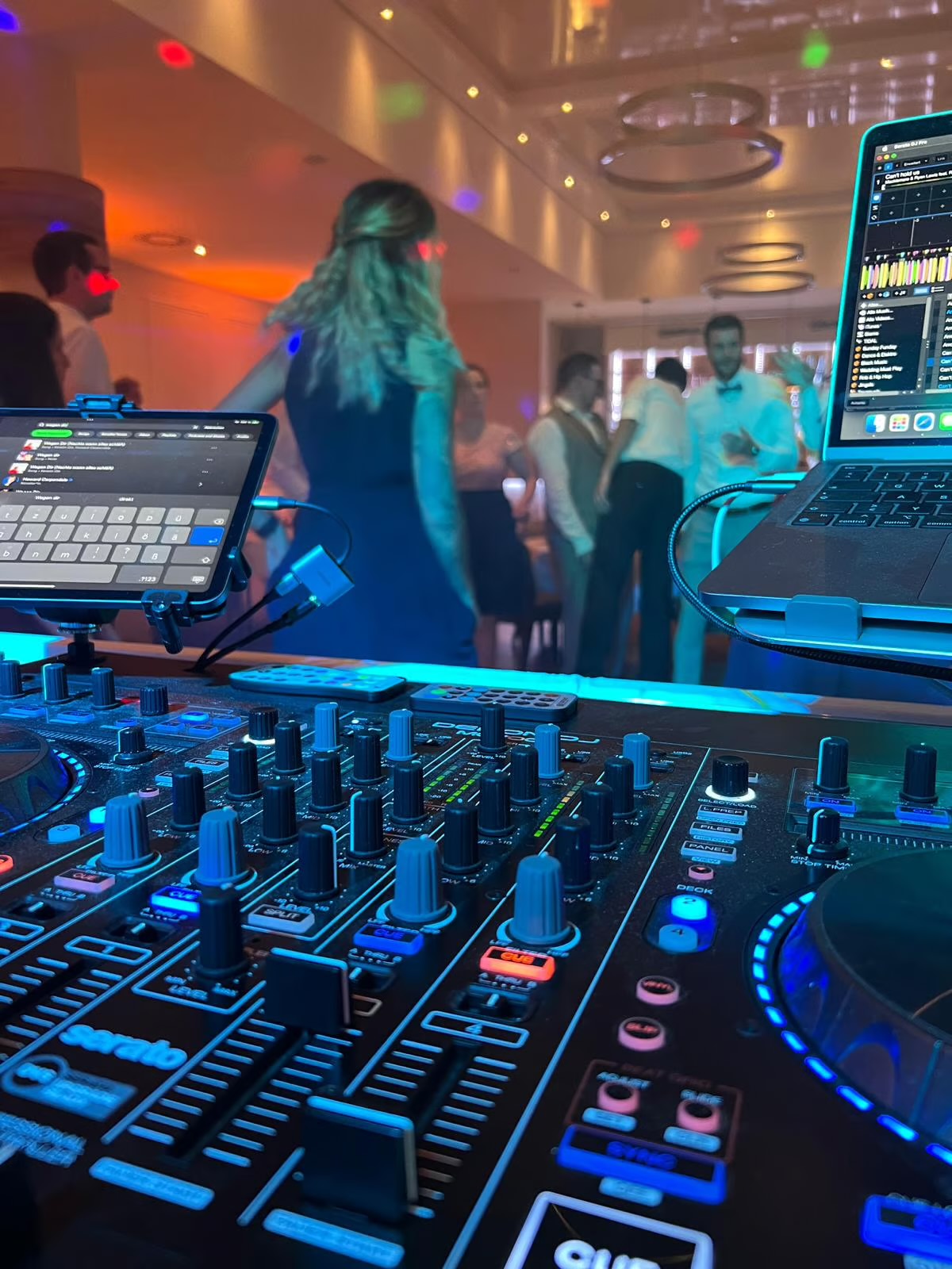 Blick über das DJ-Pult auf die tanzenden Gäste