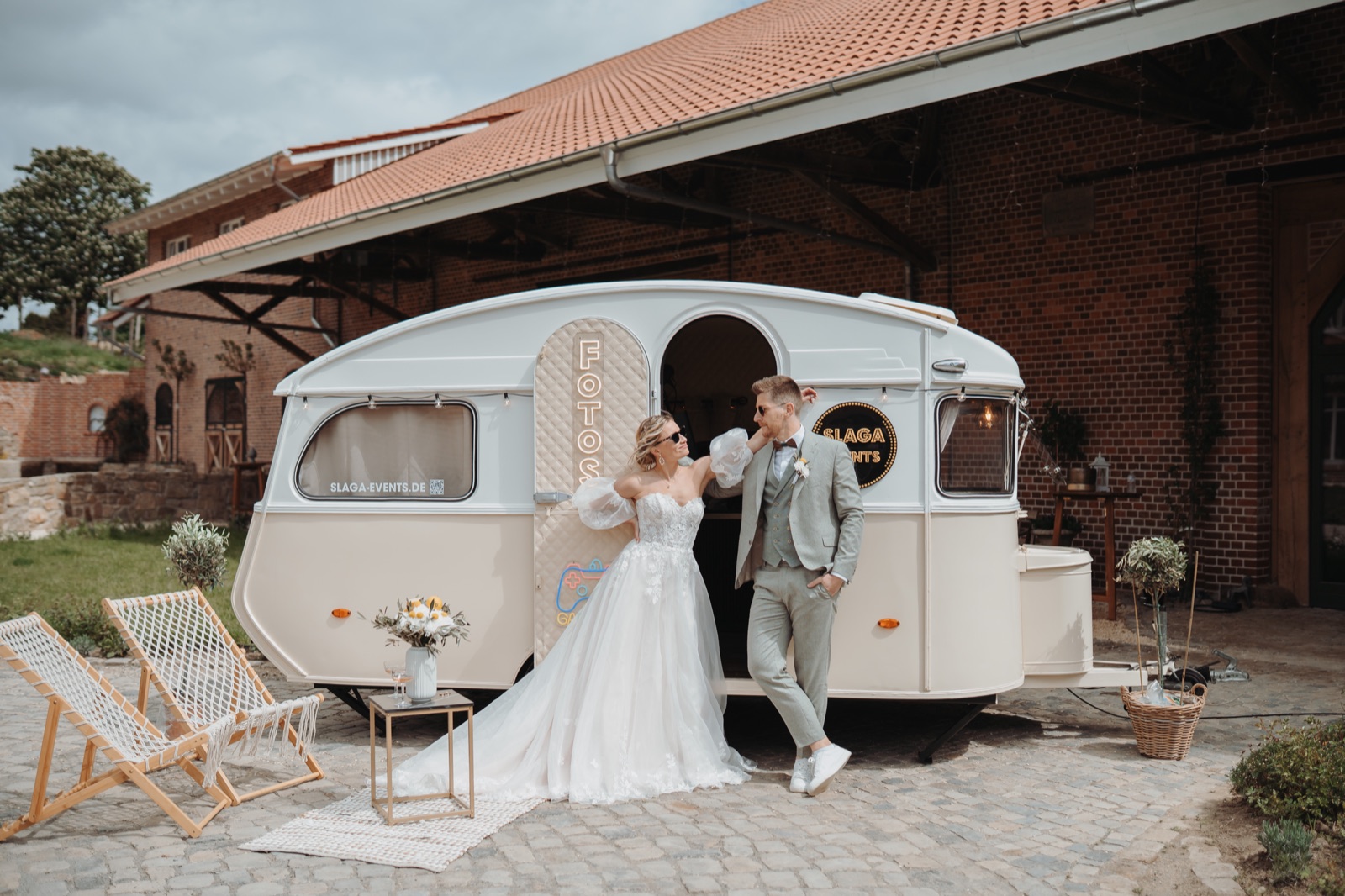 Brautpaar lehnt am Foto-Caravan von SLAGA Events