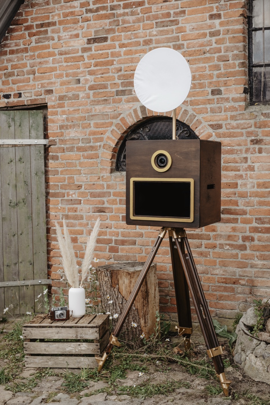 Retro-Fotobox aus Holz auf Stativ vor einer Backsteinwand